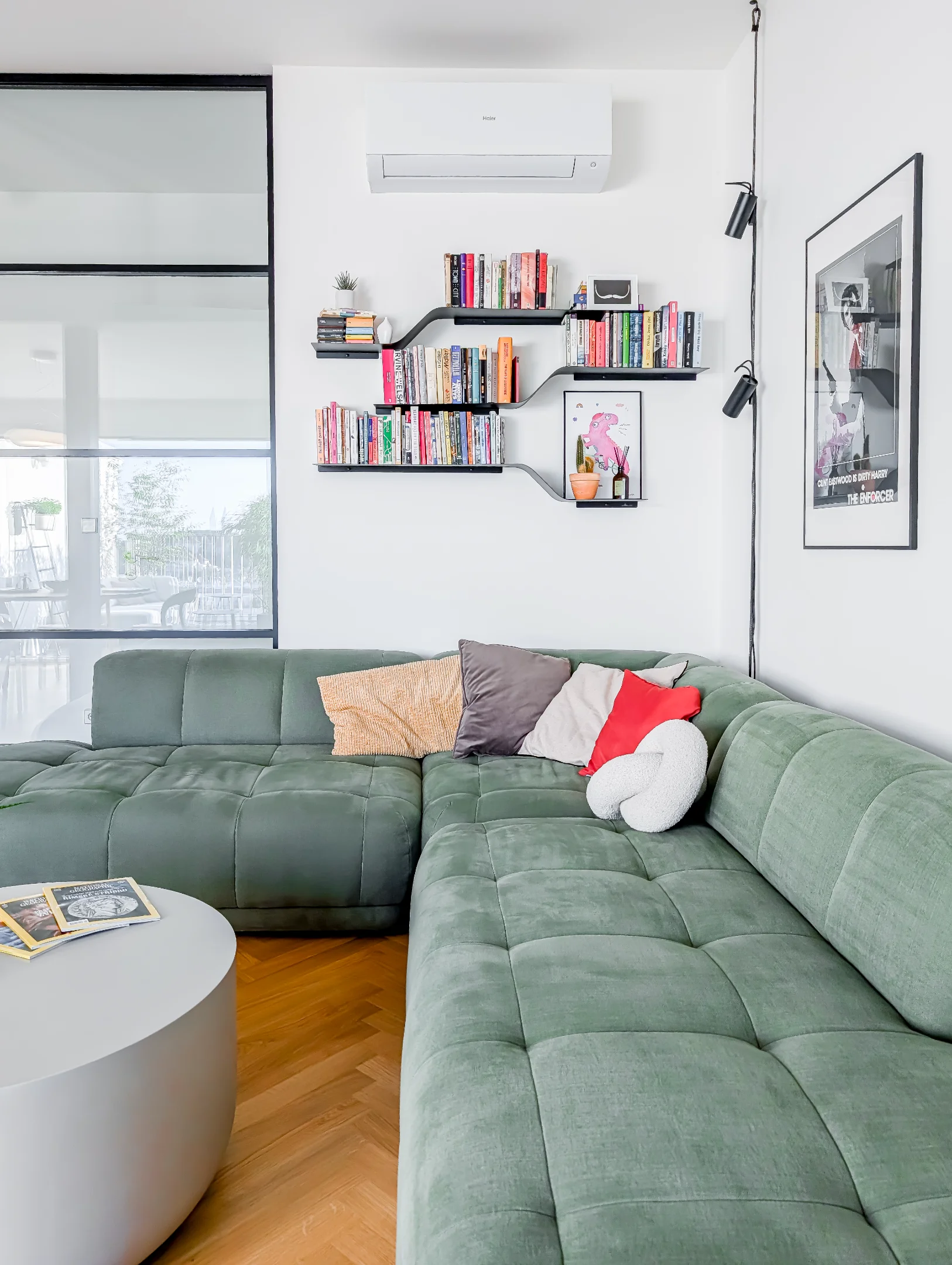 Zelená sedačka, police s knihami, moderní interiér bytu.